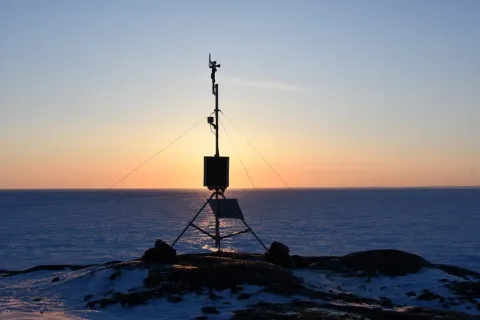 Sun setting behind weather station based on WIRL's Cryologger Automatic Weather Station design.